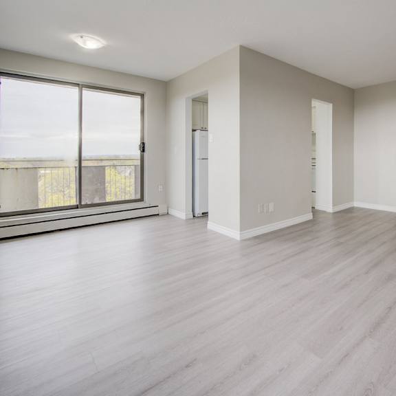 a spacious room with wooden flooring and white walls.