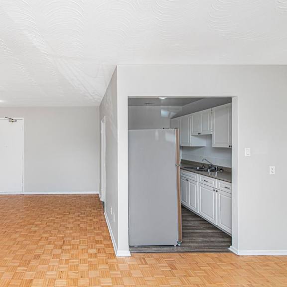 a kitchen area with a refrigerator, sink, and cabinets.
