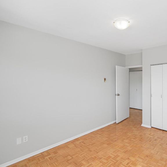 a room with white walls and wooden flooring with three white doors.