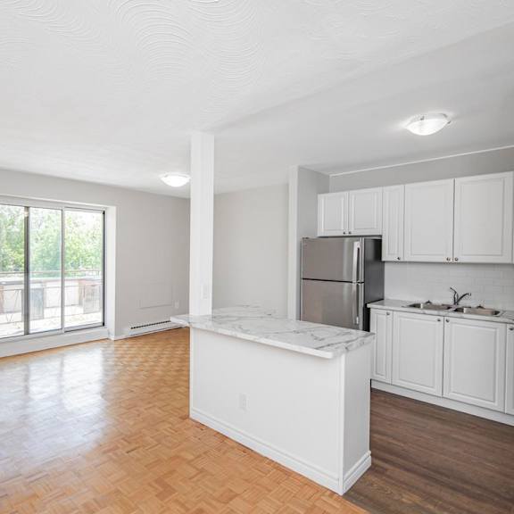 a kitchen with white cabinets and a marble island.