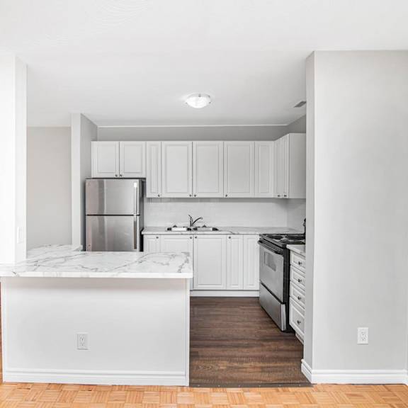 a kitchen with white cabinets and a marble island.