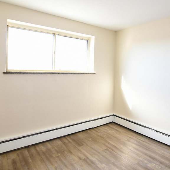 a room with a window and wooden flooring.