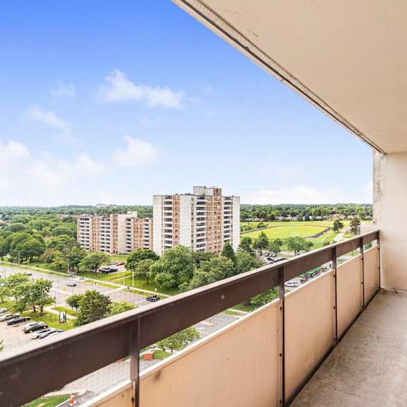 a balcony with a view of a parking lot and buildings.