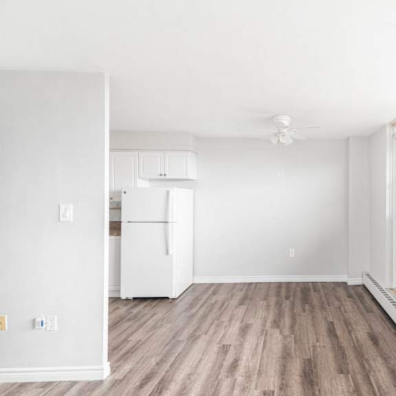 a white fridge in a room with wooden floors and white walls.