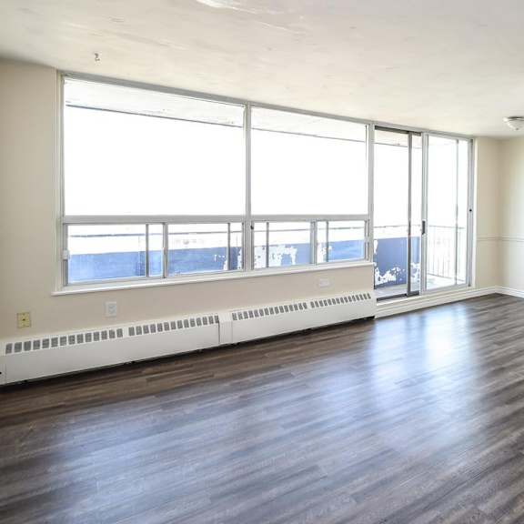 a large empty room with wooden floors and a view of the outside through the windows.