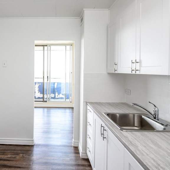 a kitchen with white cabinets and a wooden floor.