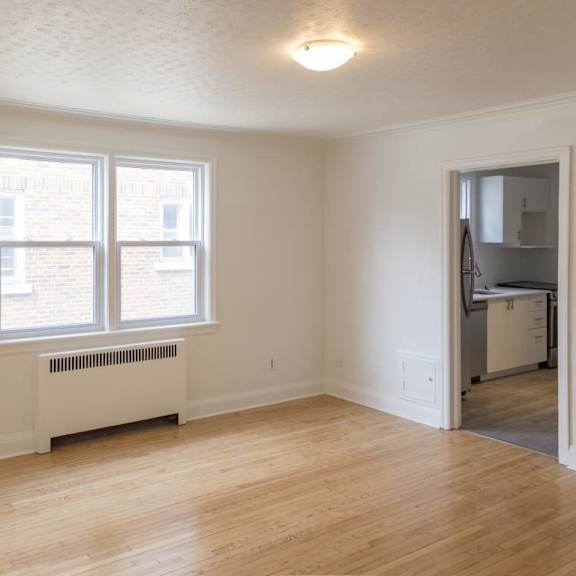 a room with a white wall and a window with a white radiator beneath it.