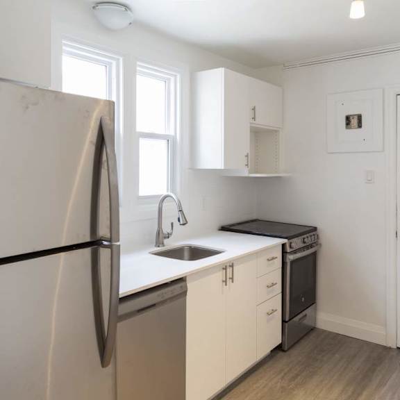 a kitchen with white cabinets and a black fridge.