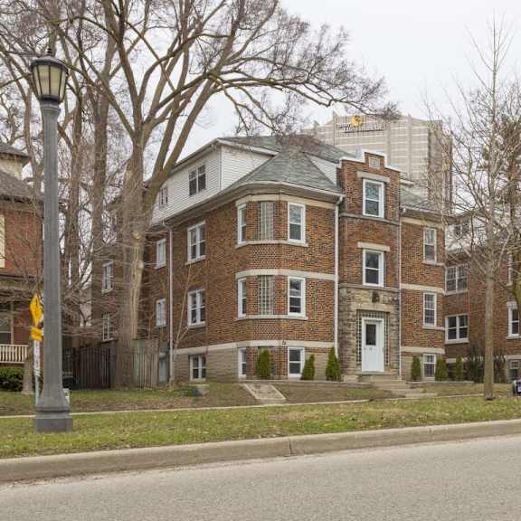a large brick building with a green roof sits on a street corner.