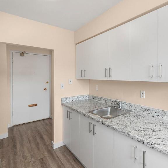 a kitchen with white cabinets and a marble countertop.