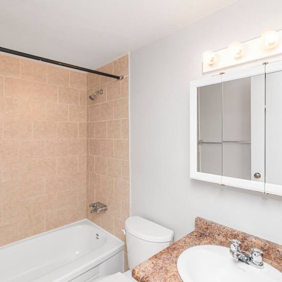a bathroom with a white tub, toilet, and sink.