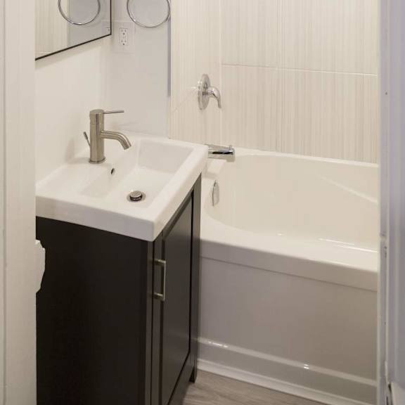 a white sink with a silver faucet is on a black countertop.