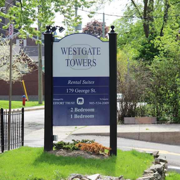 a sign for westgate towers rental suites stands in front of a building.