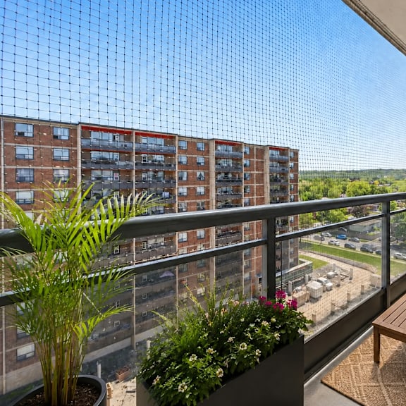 a balcony with a couch, table, and plants overlooks a cityscape.