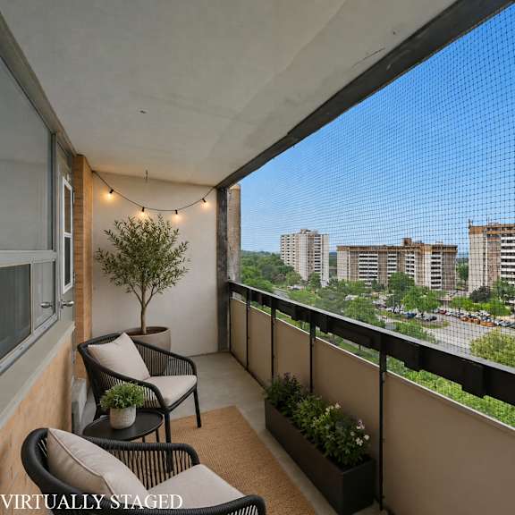 a balcony with a chair and a table overlooking a cityscape.