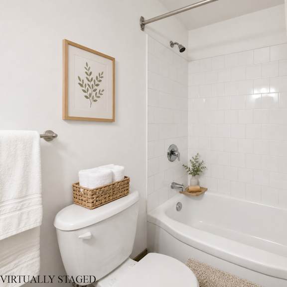 a white bathroom with a towel, a basket, and a plant.