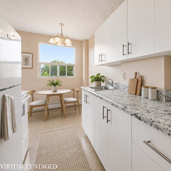 a kitchen with white cabinets and a marble countertop.