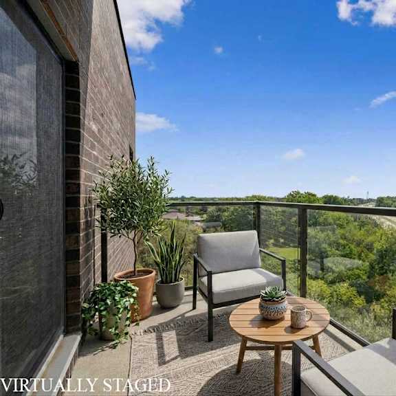 a balcony with a table and chairs overlooking a highway.
