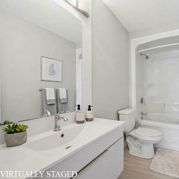 a white bathroom with a toilet, sink, and bathtub.