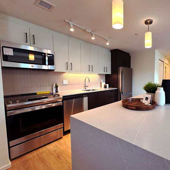 a modern kitchen with a white island and stainless steel appliances.at imperium, dundas ontario