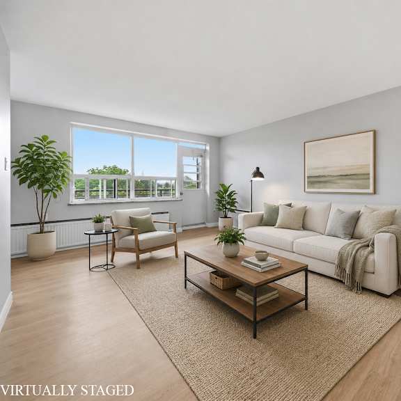 a living room with a white couch, a coffee table, and a large window.