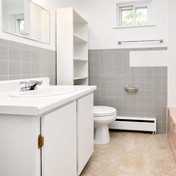 a white bathroom with a pink tub and grey tiles.