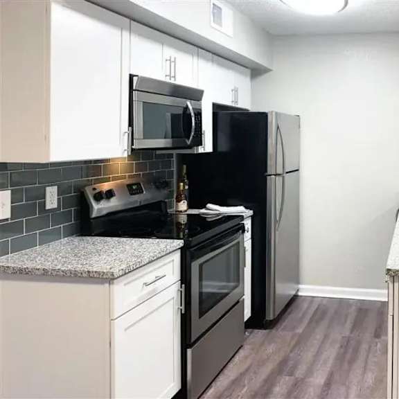 a kitchen with black appliances and white cabinets. at latitude at riverchase, hoover, al, 35216