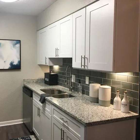 a kitchen with a black refrigerator and white cabinets. at latitude at riverchase, hoover, al, 35216