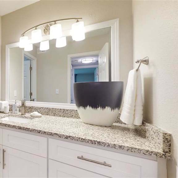 a bathroom with a marble countertop and a large mirror. at vinings rivervue, georgia