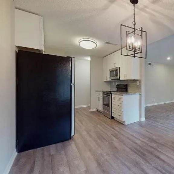 a kitchen area with a black refrigerator and a wooden floor. at spalding vue, peachtree corners, 30092