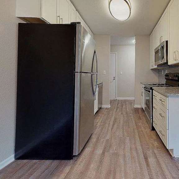 a black refrigerator is in the corner of a kitchen with wood flooring. at spalding vue, peachtree corners, 30092