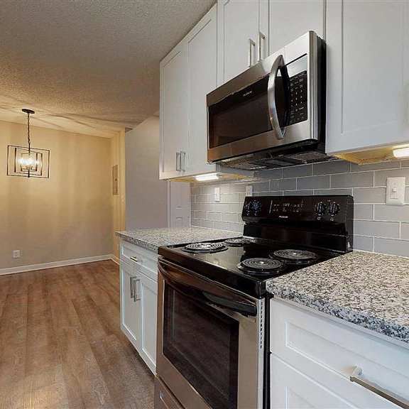a kitchen with a black microwave above the stove. at vue on medlock, peachtree corners, ga, 30092