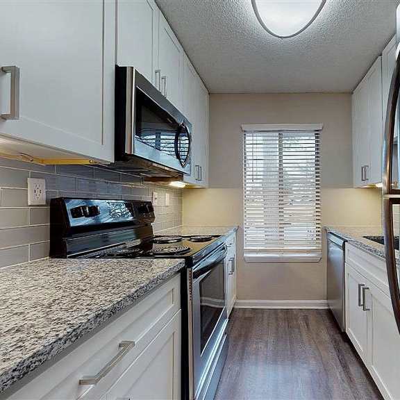 a kitchen with a stove top oven and a microwave above it. at vue on medlock, peachtree corners, georgia