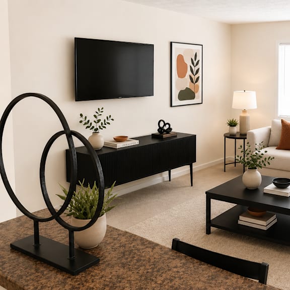 a living room with a black sofa, a white couch, and a tv mounted on the wall.