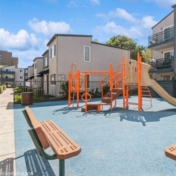 a playground with a slide and swings in front of a building at oak center apartments, oakland, california