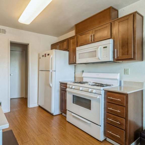 a kitchen with white appliances and wooden cabinets at oak center apartments, oakland