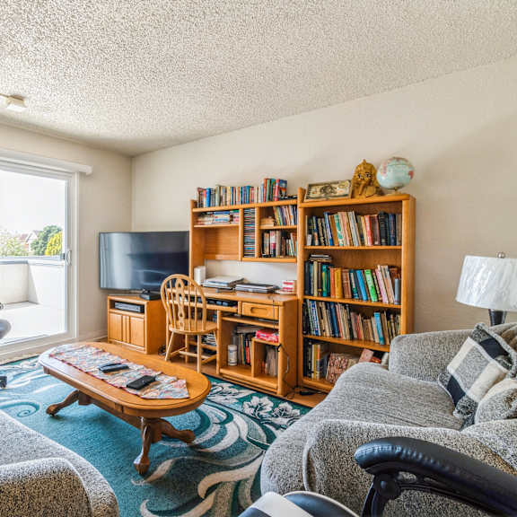 a living room with a grey couch, a wooden bookshelf, and a coffee table at oak center apartments, oakland, 94607