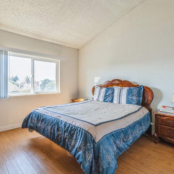 a bedroom with a bed, nightstand, and window at oak center apartments, oakland, 94607