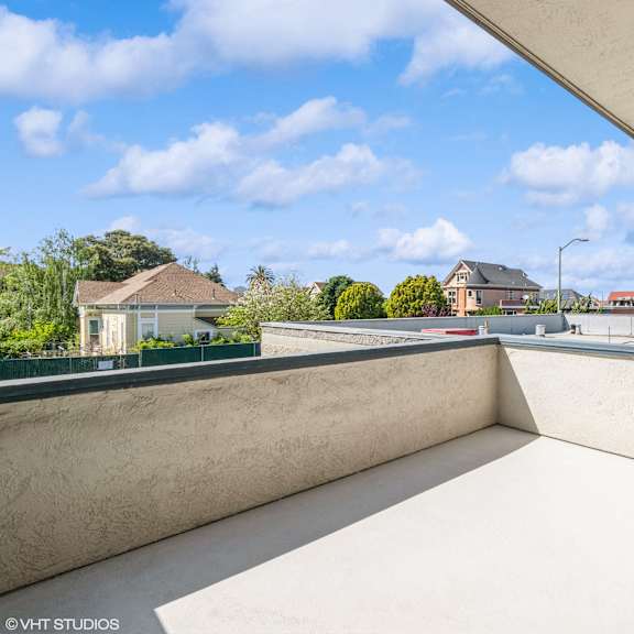 a balcony with a potted plant on the edge overlooks a residential area at oak center apartments, oakland, ca, 94607
