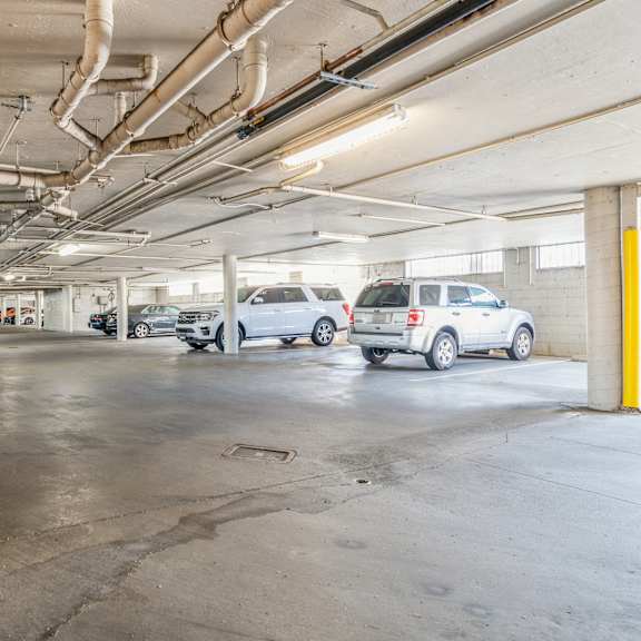 a parking garage with several cars parked and a yellow pole on the right side at oak center apartments, california, 94607