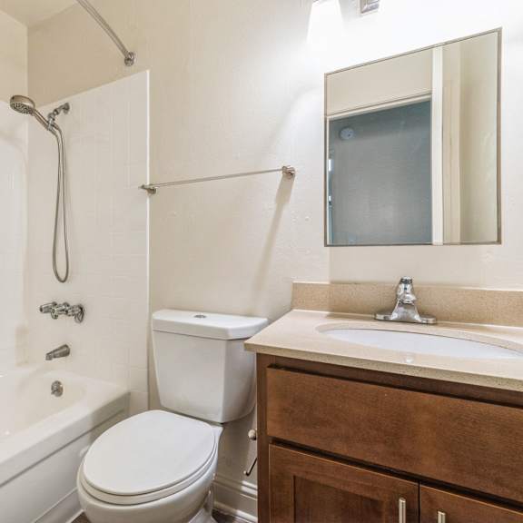 a white bathroom with a toilet, sink, and tub at oak center apartments, california