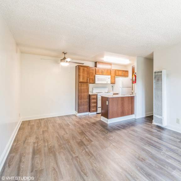 a spacious room with wooden flooring and a kitchenette in the background at oak center apartments, california, 94607