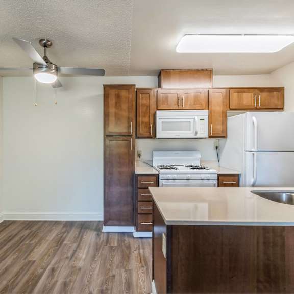 a kitchen with wooden cabinets and a white fridge at oak center apartments, california