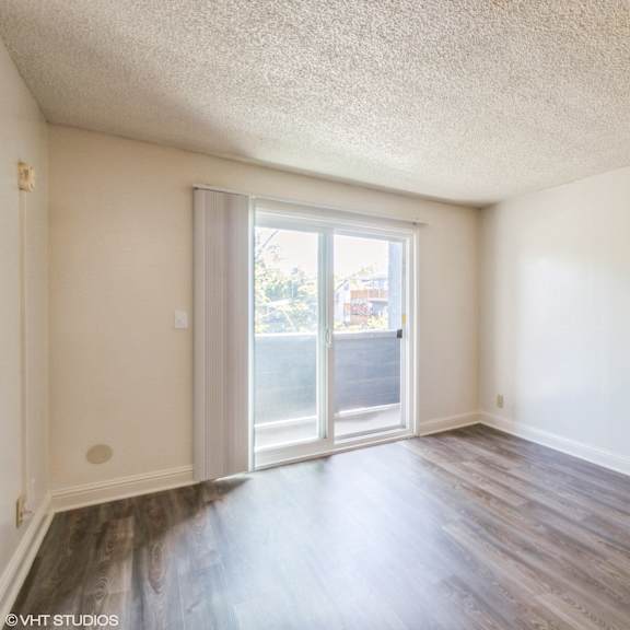 a room with a sliding glass door leading to a balcony at oak center apartments, oakland