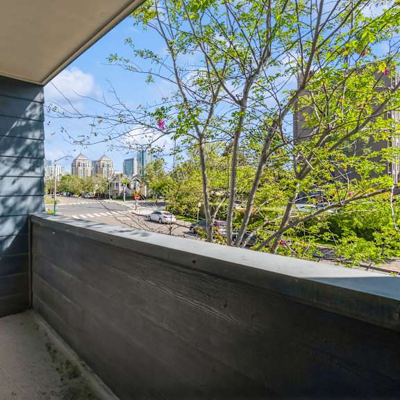 a balcony with a view of a cityscape and trees. at oak center apartments, oakland, ca, 94607