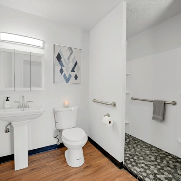a white bathroom with a toilet, sink, and shower at fullerton court apartments, chicago, illinois