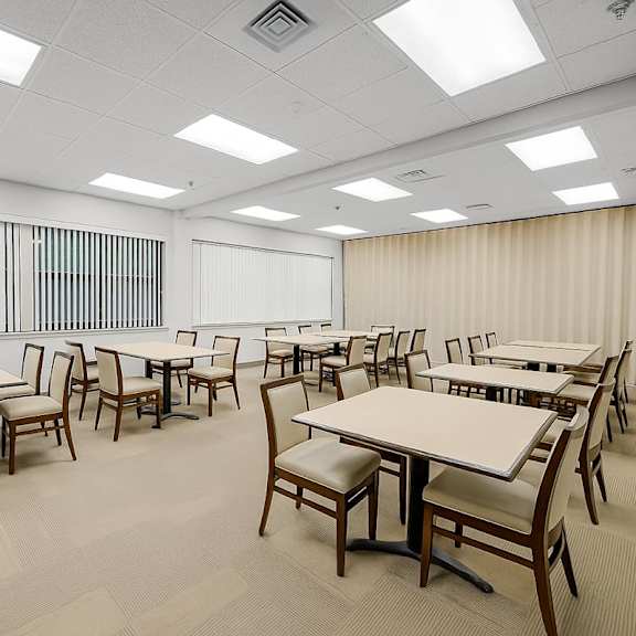 a room with tables and chairs and a window with bars at fullerton court apartments, illinois