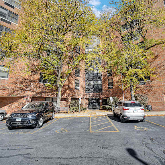 a black suv is parked in a parking lot in front of a brick building at fullerton court apartments, chicago, 60614