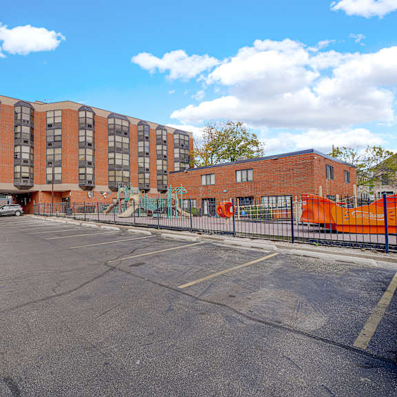 a parking lot in front of a multi-story brick building at fullerton court apartments, chicago