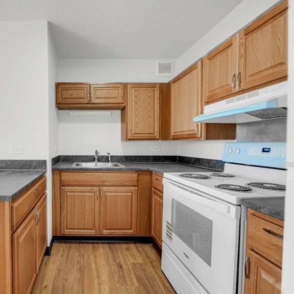 a kitchen with wooden cabinets and a white stove top oven at fullerton court apartments, chicago, il 60614